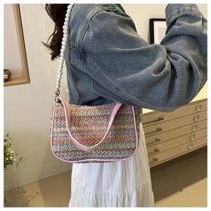 Detail of colorful woven straw bag with pearl shoulder strap and butterfly embroidery