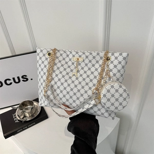 White tote bag with black geometric chain print and gold deer charm in a stylish setting