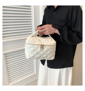 Close-up of a cream quilted vanity case with gold zippers and a stylish lattice pattern