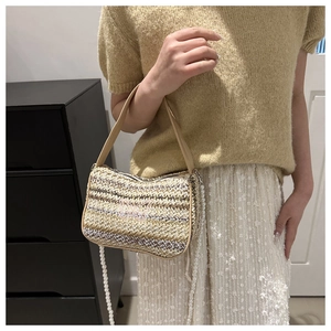 Close-up of woven straw bag featuring pink butterfly embroidery and pearl strap detail