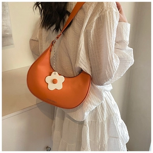 Close-up of orange hobo shoulder bag with daisy charm and embossed brand text
