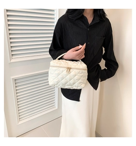 Borsa cosmetica trapuntata bianca con cerniere dorate, mostrata con un outfit alla moda