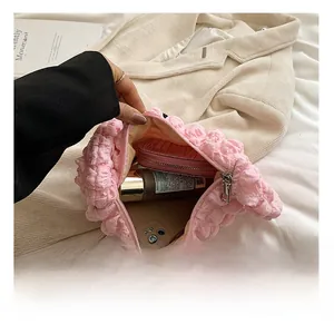 Detailed interior of pink textured dumpling bag showing storage for phone and cosmetics