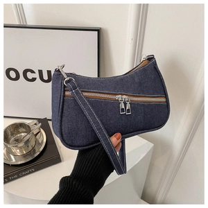 Dettaglio della borsa baguette in denim con cuciture bianche e zip in metallo argento