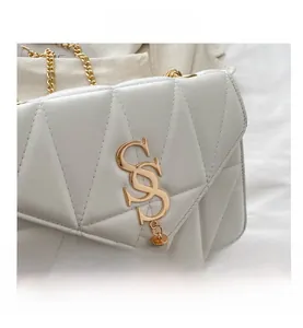 Detail of white quilted handbag with gold S-logo, fringe tassels and metal chain strap