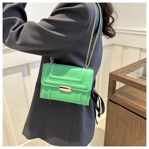 Detail of bright green textured mini bag with golden metal clasp and chain strap