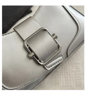 Detailed macro view of silver metallic leather handbag with large square metal buckle