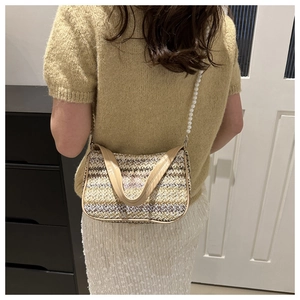 Detail of colorful woven straw bag featuring pearl strap and beige handles on a model