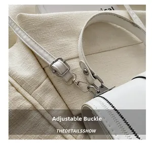 Macro view of silver metal buckle and contrast stitching on white leather handbag