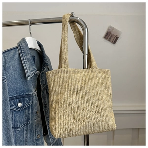 Dettaglio della borsa tote in paglia intrecciata beige con ampi manici a spalla