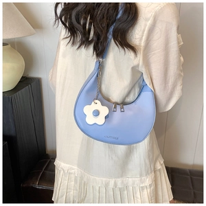 Detail of light blue crescent hobo bag with matte leather and white flower charm accessory