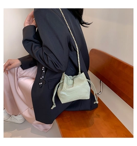 Detail of mint green drawstring bucket bag with gold chain strap on a model