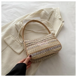 Detail of summer straw woven bag with pink butterfly embroidery and pearl chain strap