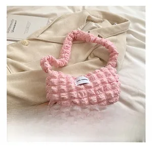 Detail of light pink bubble textured fabric handbag with LOVE FASHION woven label