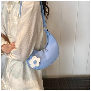 Detail of light blue crescent underarm bag with a white flower charm and zipper