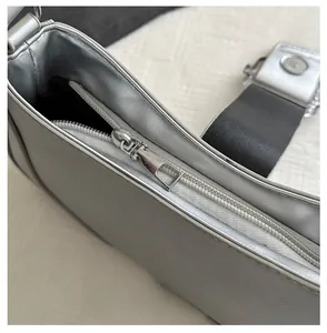 Detailed close-up of smooth silver metallic shoulder bag zipper with durable metal puller