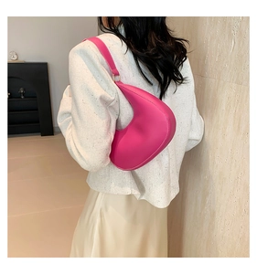 Détail du sac à bandoulière fuchsia en forme de croissant avec texture en cuir mat