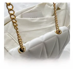 Detail showing white quilted leather texture with gold chain and metal grommet design