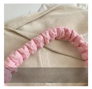 Detail showing the pink pleated handle and beige corduroy texture of the shoulder bag