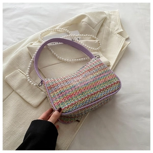 Detail of colorful woven straw bag with butterfly embroidery and pearl strap