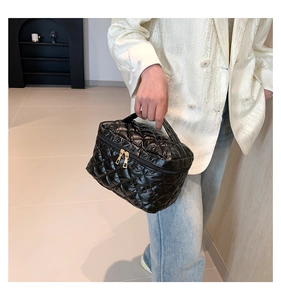 Dettaglio della borsa da toilette trapuntata nera con cerniere dorate per donne