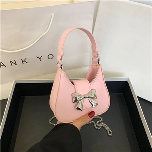 Pale pink bow handbag with silver chain strap and metal clasp shown by hand in high quality