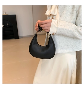 Détail d'un sac hobo noir avec finition en cuir mat et attaches à anneaux dorés