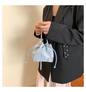 Detail of light blue bucket bag with gold chain strap and textured leather finish