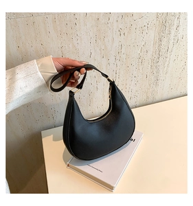 Détail du sac croissant noir avec texture grainée et finitions métalliques dorées