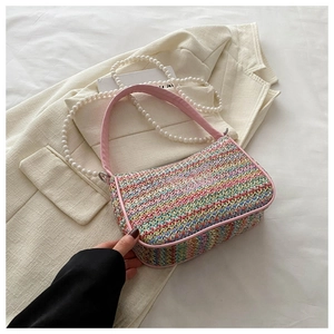 Detail of rainbow woven straw bag with pink butterfly embroidery and pearl chain strap