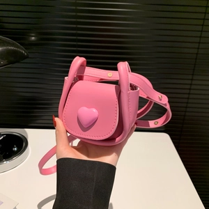 Mini pink shoulder bag with heart detail and adjustable strap for crossbody wear