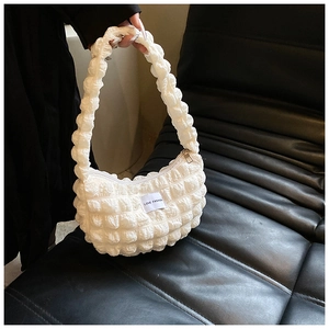 Close-up of white bubble pleated shoulder bag with LOVE FASHION label on black sofa