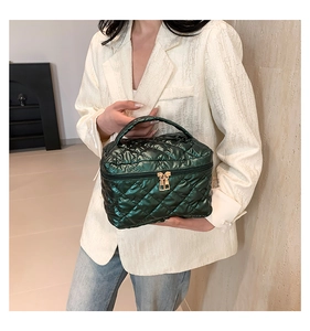 Detail of dark green quilted cosmetic bag with gold zippers and a top handle