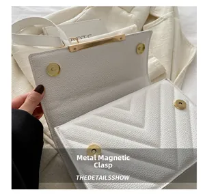 Close-up of white crossbody bag with V-shaped quilting and golden hardware buckle