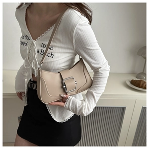 Detail of beige shoulder bag with stylish large silver metal buckle on leather strap