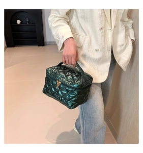 Detail of dark green quilted cosmetic bag with metallic finish and diamond stitching