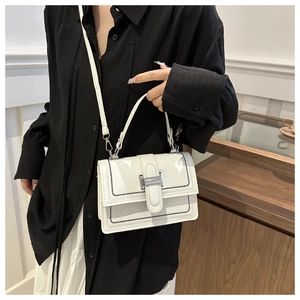 Close-up of white flap bag with black contrast stitching and silver metal buckle