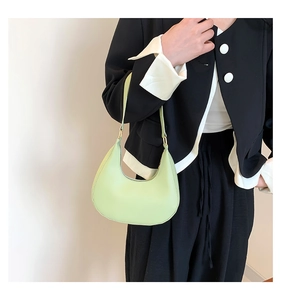 Gros plan d'un sac hobo croissant vert clair en cuir lisse avec détails dorés