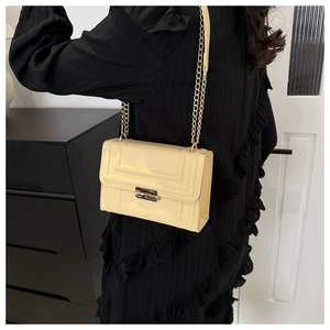 Detail of cream square shoulder bag with geometric embossing and gold chain strap