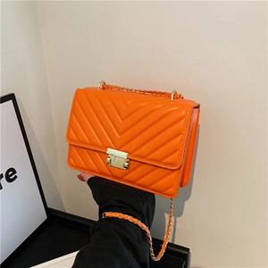 Orange V-quilted faux leather crossbody bag with gold chain strap and turn-lock closure