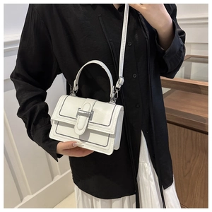 Detail of white leather handbag featuring black contrast stitching and silver metal buckle
