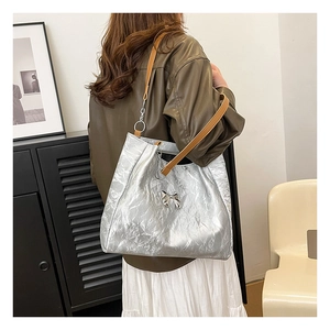 Silver velvet tote bag with metallic butterfly detail worn over the shoulder by model