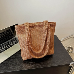 Borsa tote intrecciata color caramello con chiusura magnetica su tavolo scuro