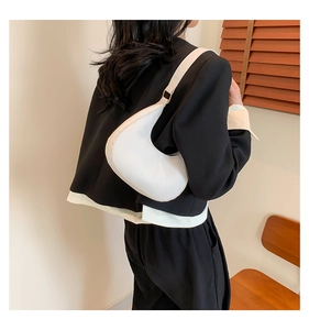 Gros plan sur un sac croissant blanc porté par un mannequin dans un décor naturel