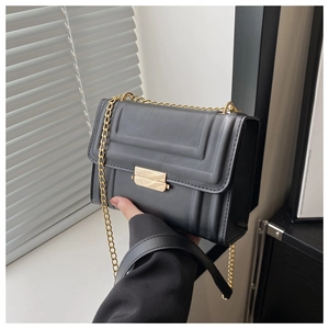 Close-up of black crossbody bag featuring matte leather texture and gold metal buckle