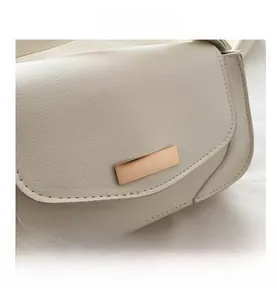 Detailed close-up of ivory crossbody bag featuring fine cross-grain texture and gold clasp