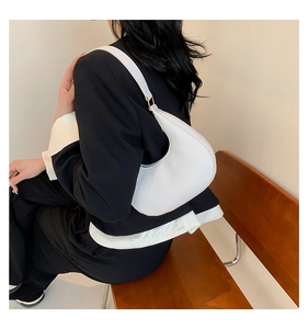 Gros plan du sac à main croissant en cuir blanc minimaliste avec détails dorés
