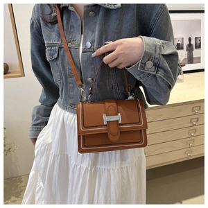 Close-up of brown crossbody bag with white stitching detail and metallic clasp
