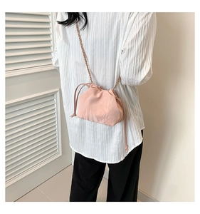 Detail of pink drawstring crossbody bag with pleated texture and metal chain strap