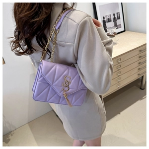 Detail of purple quilted crossbody bag with gold chain strap and stylish tassel pendant